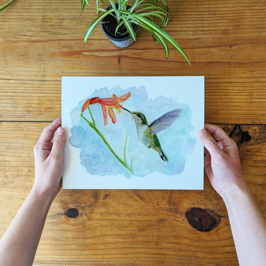 a person holding a card with a picture of a hummingbird on it