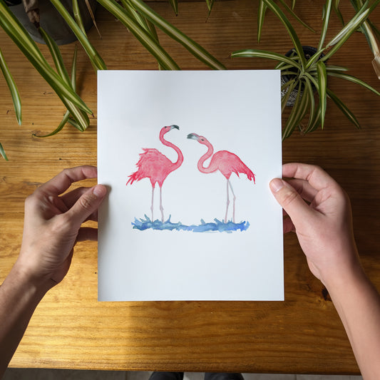 a person holding a card with two pink flamingos on it