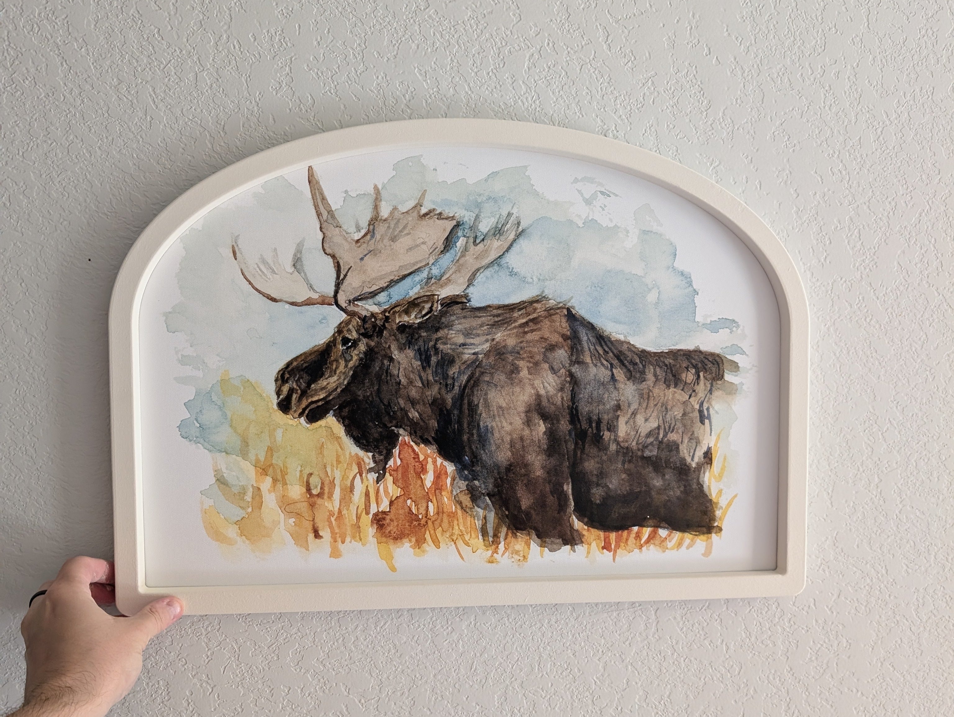 Framed artwork of a moose on a plain wall