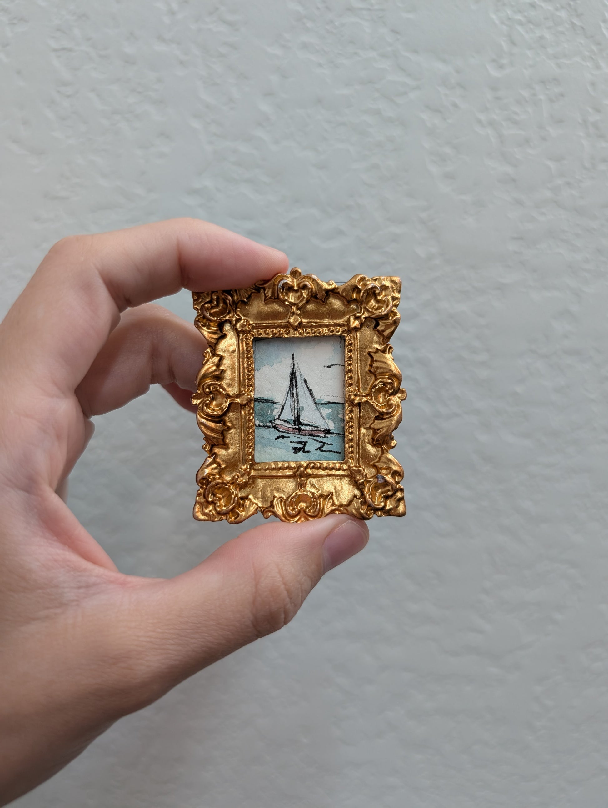 a person holding a small picture frame with a boat on it