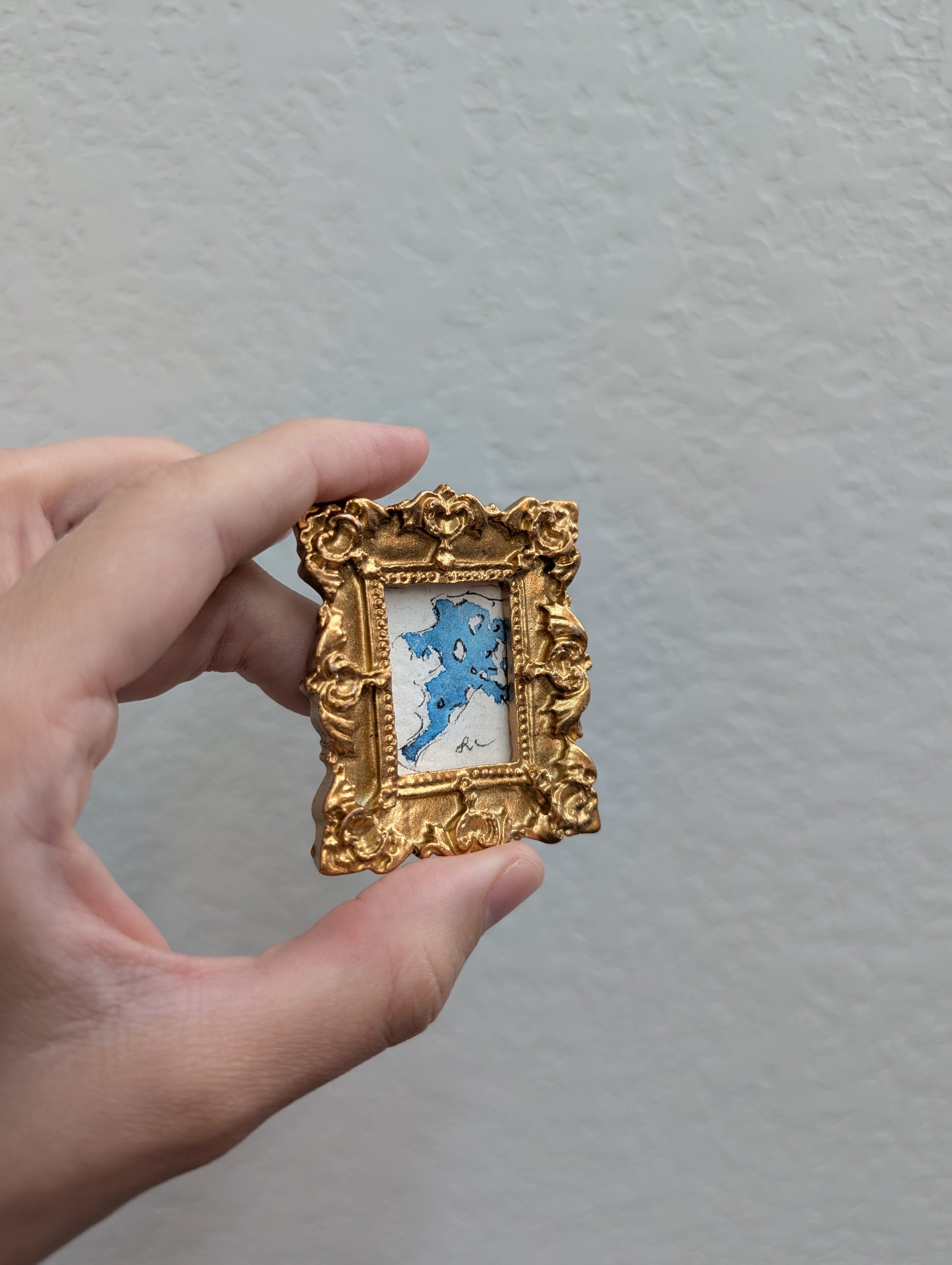 a person holding a small picture frame in their hand