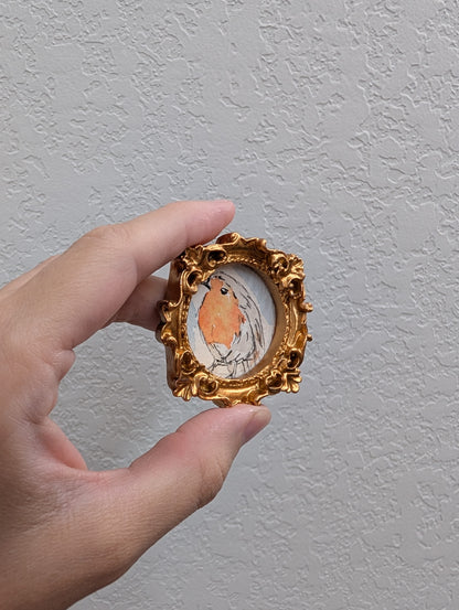 a hand holding a miniature picture of a bird