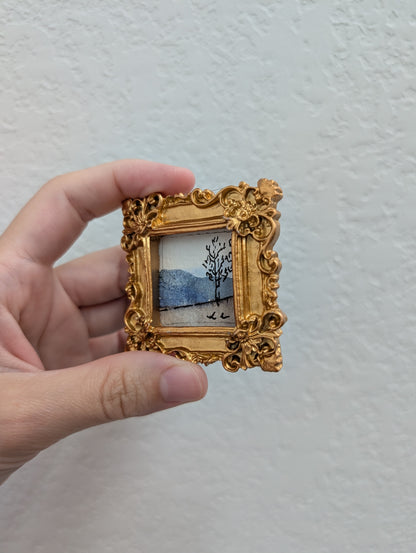 a person holding a small picture frame with a painting on it