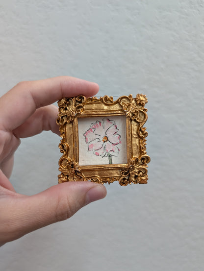 a person holding a small picture frame with a flower on it