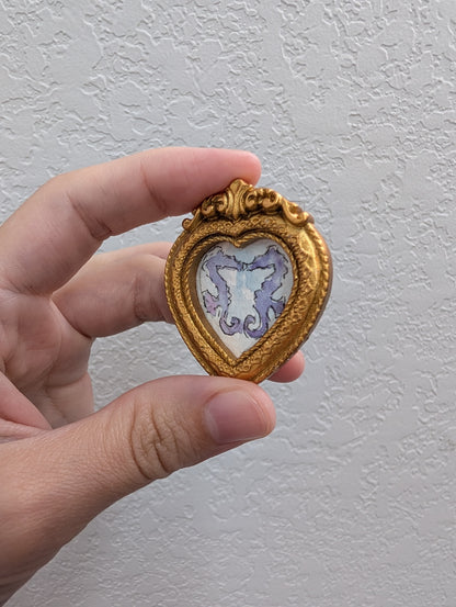 a hand holding a small heart shaped brooch
