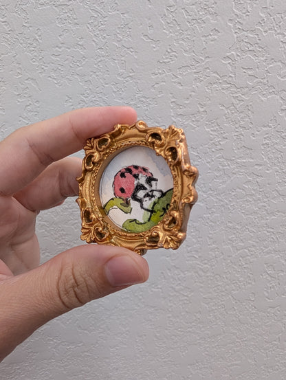 a hand holding a picture frame with a picture of a ladybug on it
