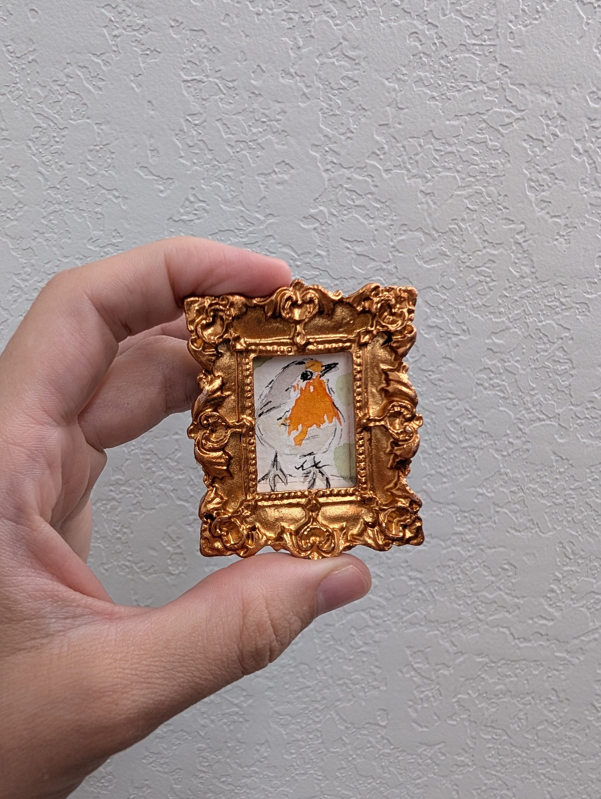 a hand holding a small gold frame with a picture of a horse