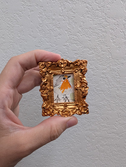 a hand holding a small gold frame with a picture of a horse