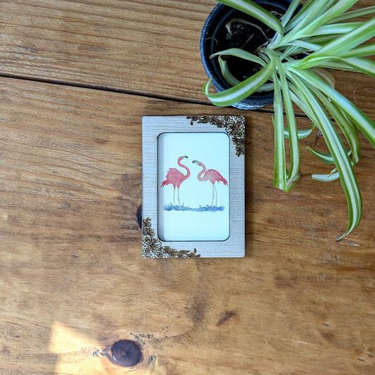 a picture of two flamingos on a wooden table